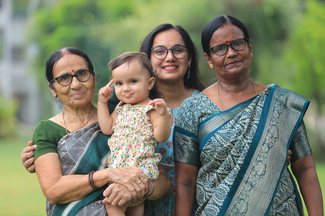 Parents holding their young child's hands on a walk