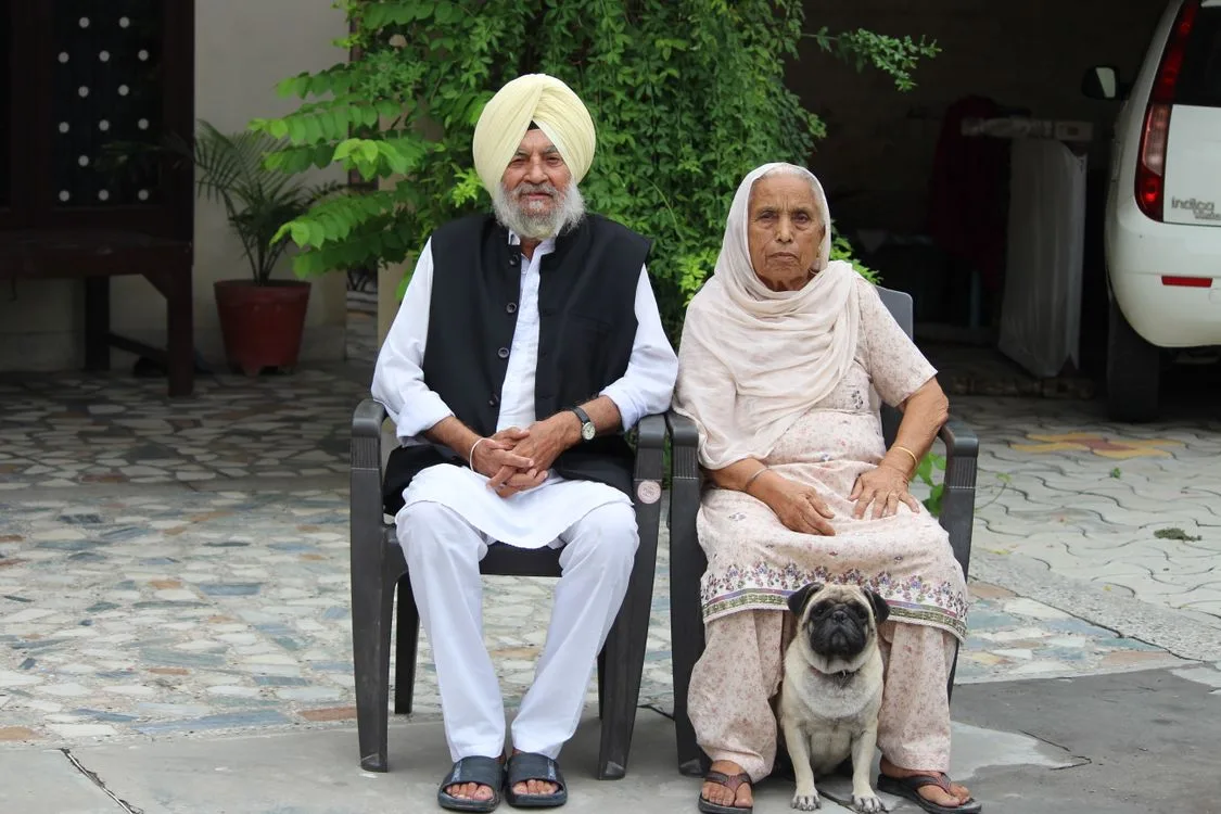 Elderly couple sitting with their dog outside their home