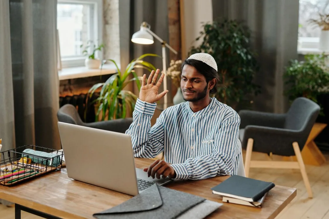 Man waving hello during a video call from his home office