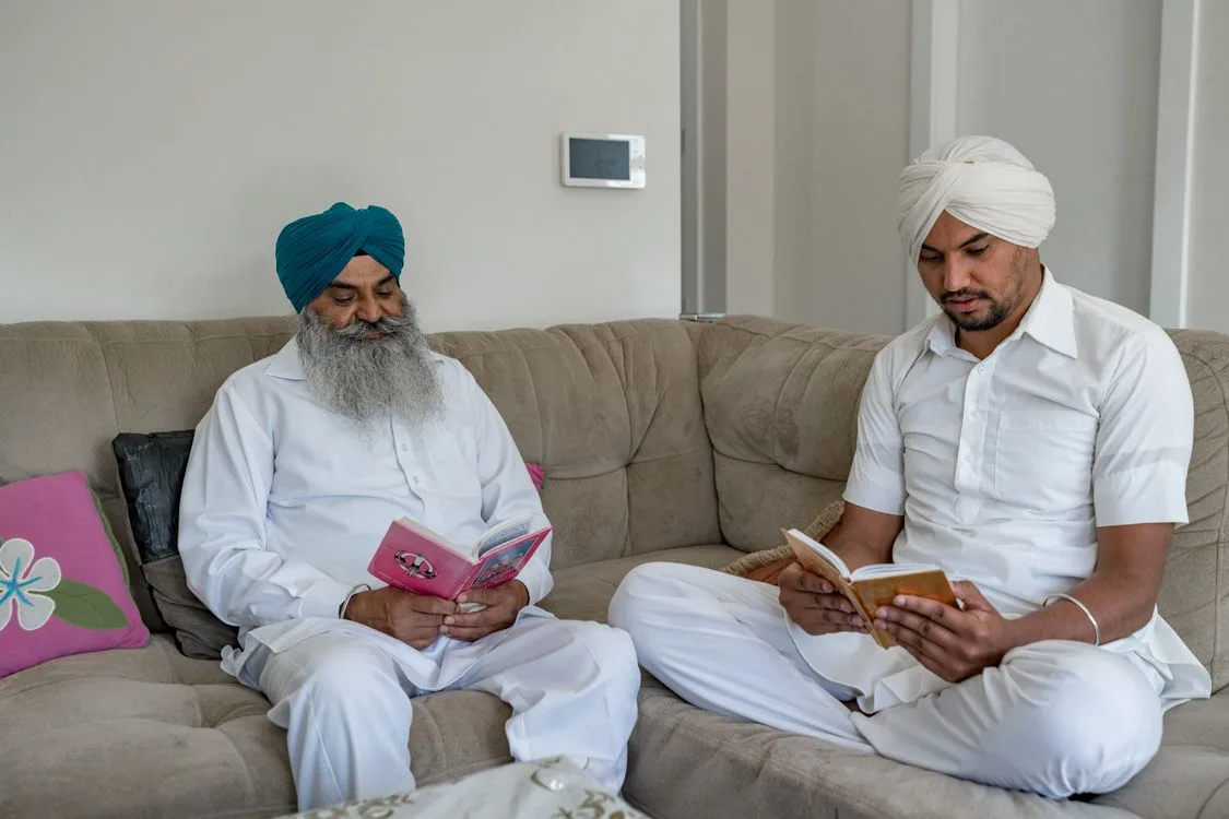 Elderly man and younger man reading together in a living room