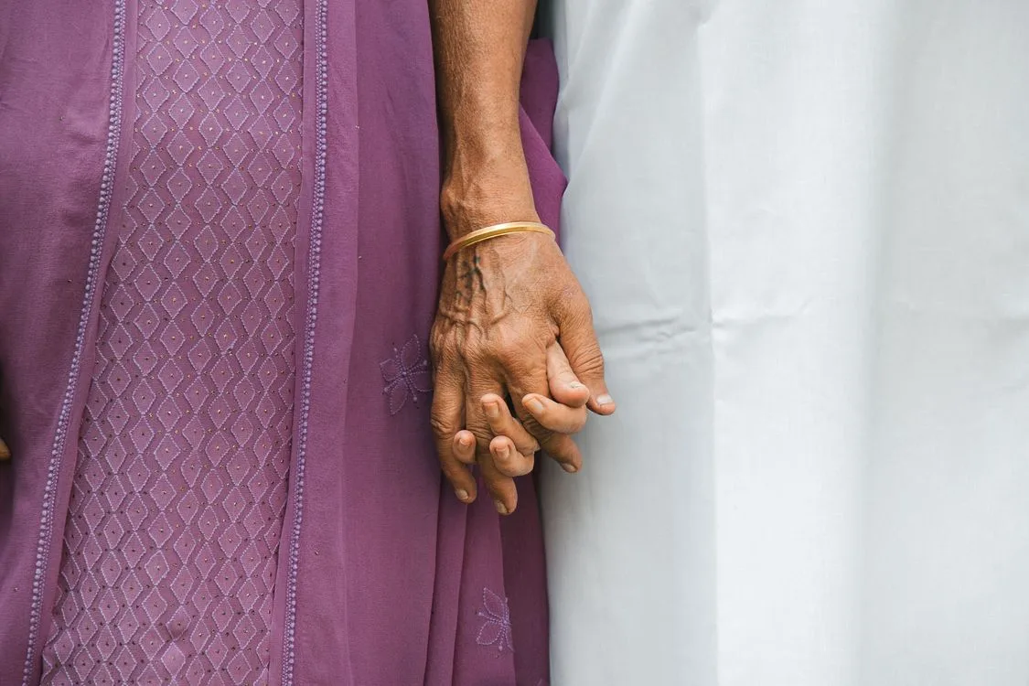 Younger woman gently holding an elderly woman's hand